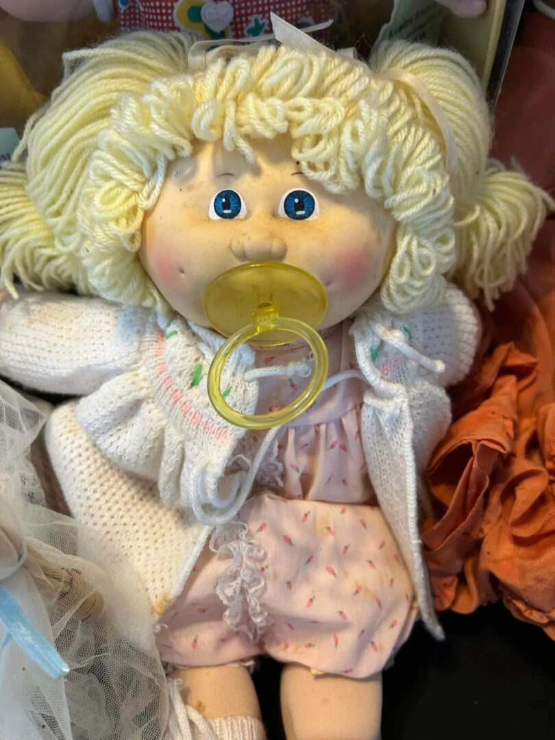 A doll with a pacifier in its mouth.