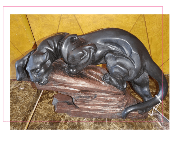A black dog statue sitting on top of a log.